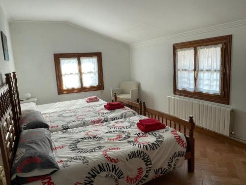 a bedroom with two beds and two windows at Casa rural Amillano in Amillano