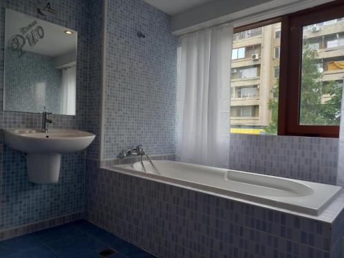 baño con bañera, lavabo y ventana en Hotel Rio en Nova Zagora
