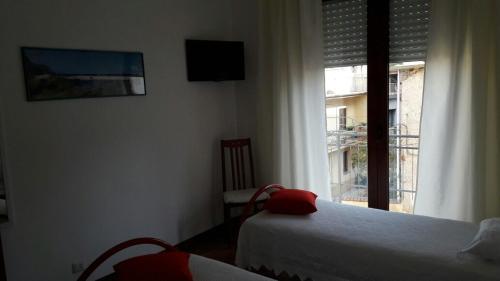 a bedroom with a bed and a window with a television at La fontanella in Loceri