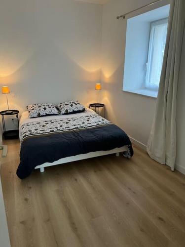 une chambre avec un lit et deux lampes et une fenêtre dans l'établissement Petite maison au calme proche bourg, à Le Pener