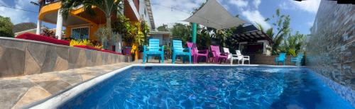 a swimming pool with chairs and tables and a building at Posada Ashanty in Providencia