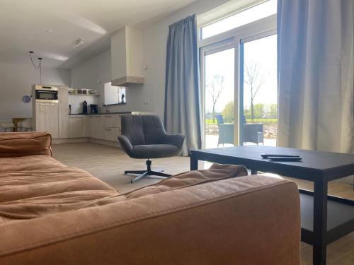 a living room with a couch and a table and a kitchen at Vakantiehuis Buitengewoon in Beers