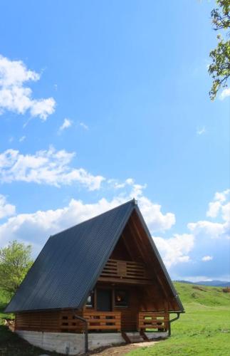 a large wooden cabin with a black roof at Peća in Glamoč