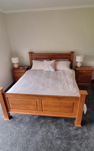 a bedroom with a wooden bed with two night stands at Wellington marina70 in Wellington East