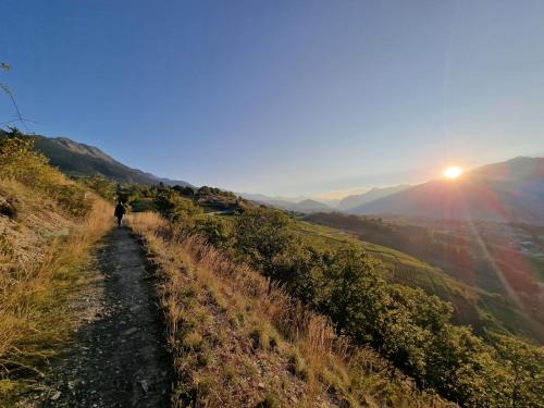 a person walking down a path on a hill at sunset at Bella Flocon appartements min 2 Nights Special weekly and monthly prices in Savièse