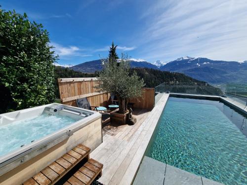 a hot tub on a deck with a view of mountains at Bella Flocon appartements min 2 Nights Special weekly and monthly prices in Savièse