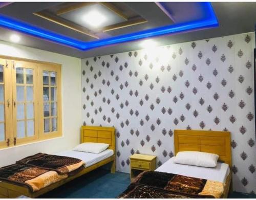two beds in a room with a blue ceiling at Skardu city Guest house in Skardu