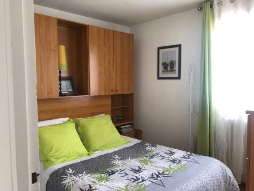 ein Schlafzimmer mit einem Bett mit grünen Kissen in der Unterkunft Chelles - Paris - Disneyland Marne la vallée in Chelles