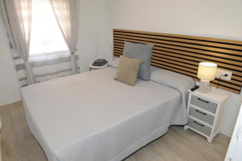 a bedroom with a large white bed with a wooden headboard at La coqueta in Murcia