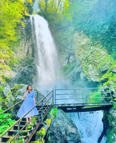 a woman standing on a bridge in front of a waterfall at Eco cottage sunrise merisi in Merisi