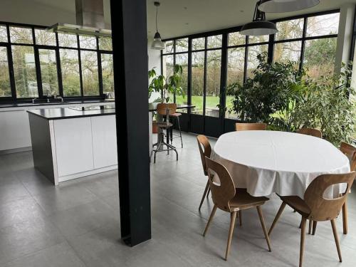 une cuisine et une salle à manger avec une table et des chaises blanches dans l'établissement Maison de caractère, à Saint-Mars-sous-Ballon