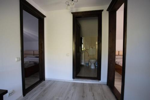 a room with two mirrors and a bathroom with a toilet at Casa din Livadă, Poiana Mărului, Brasov in Poiana Mărului