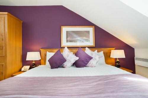 a bedroom with a large bed with purple walls at Abbey Hotel Golf & Spa in Redditch