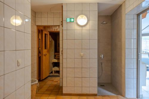 a tiled hallway with a shower in a building at Logis Hostellerie Motel Au Bois Le Sire in Orbey