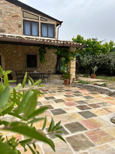 a stone patio with chairs and a building at Antico casale Sofia in Sortino