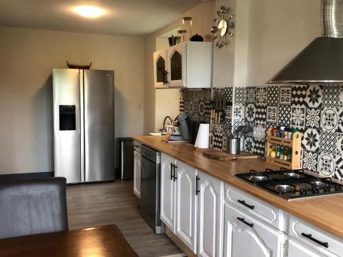 a kitchen with a stainless steel refrigerator and wooden counter tops at Le gîte aux ânes du Sancerrois in Menetou-Râtel