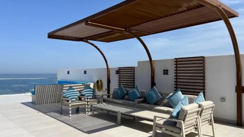 een patio met een bank en stoelen op een dak bij Seascape Villa in Fujairah