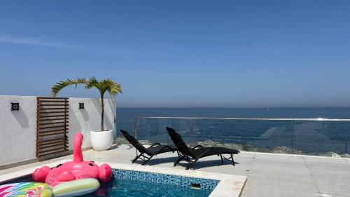 a swimming pool with two chairs and a pink inflatablelatable animal at Seascape Villa in Fujairah