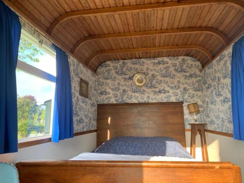a bedroom with a bed with blue walls and a wooden ceiling at In de Wolf in Watervliet