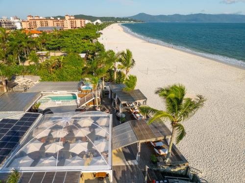 an aerial view of a beach with palm trees and a building at Pousada dos Sonhos in Florianópolis