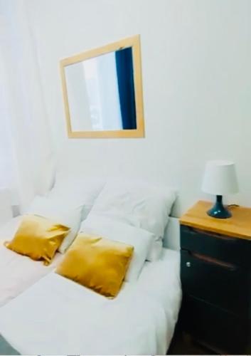 a white bed with yellow pillows and a mirror at CitizenA Studio no smoking in Radom