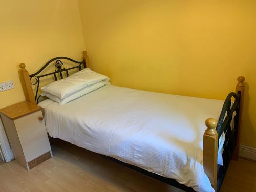 ein Schlafzimmer mit einem weißen Bett und einer gelben Wand in der Unterkunft Sheraton Lodge Apartments t12e309 in Cork