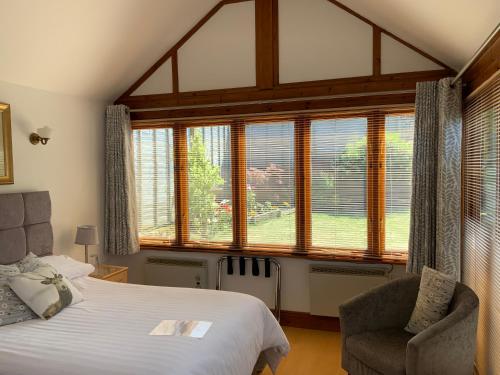 a bedroom with a bed and a chair and windows at Whortleberry Studio B & B in Porlock