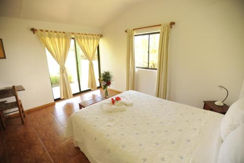 a bedroom with a white bed with flowers on it at Hotel Vai Moana in Hanga Roa