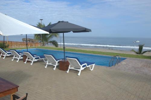 a group of chairs and umbrellas next to a pool at Hotel Gran Azul Bungalows in Canoas De Punta Sal