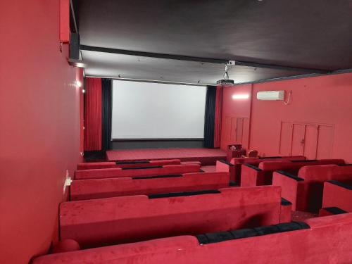 an empty theatre with red seats and a white screen at Hotel Ain Safnan Room&Flats فندق عين صفنان غرف&شقق in Sanāw