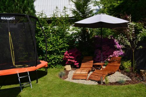 a group of chairs and an umbrella in a garden at Chata s wellness in Hutisko