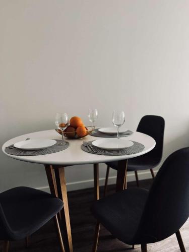 a white table with two plates and wine glasses at Milastos apartamentai in Birštonas
