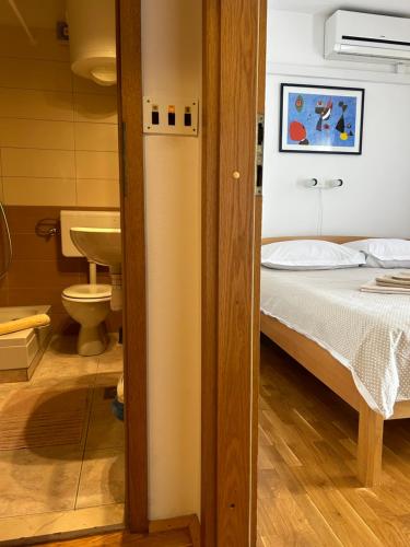 a bedroom with a bed and a bathroom with a sink at Guesthouse Fjaka in Split
