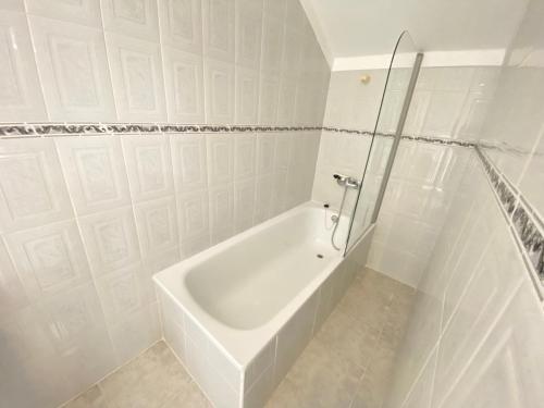 a white bathroom with a tub and a glass shower at Ericeira Sand Beach F4 in Ericeira