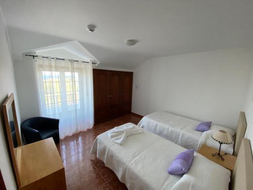 a bedroom with two beds and a chair and a window at Ericeira Sand Beach F4 in Ericeira