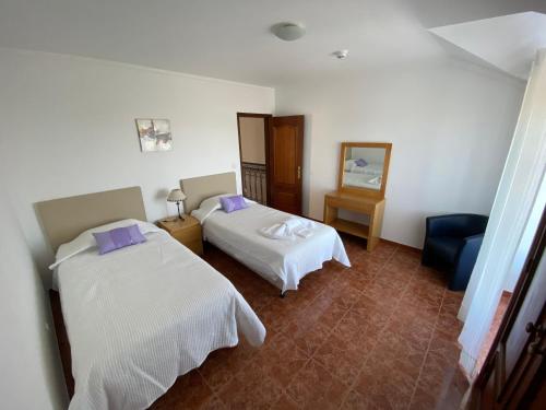 a hotel room with two beds and a chair at Ericeira Sand Beach F4 in Ericeira