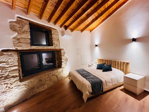 - une chambre avec un grand lit et un mur en pierre dans l'établissement The Courtyard Episkopi Guest Houses, à Episkopí