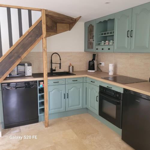 une cuisine avec des armoires bleues et des appareils noirs dans l'établissement Maison près du zoo Beauval et des châteaux de La Loire, à Noyers-sur-Cher