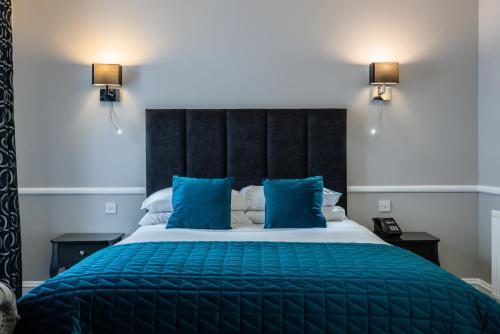 a bedroom with a large bed with blue pillows at New Inn Hotel in Ellon