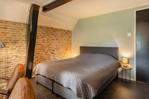 a bedroom with a bed and a brick wall at Het Koetshuis in Ruurlo