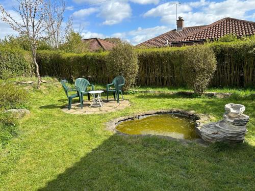 a yard with two chairs and a table and a pond at Lovely Countryside Getaway in Roslin
