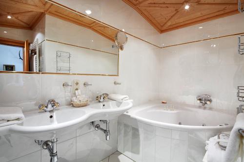 a white bathroom with two sinks and a tub at Relais & Châteaux Hotel Tennerhof in Kitzbühel