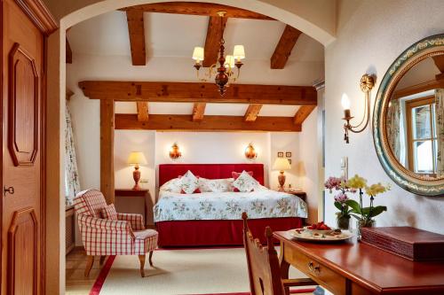 a bedroom with a red bed and a table at Relais & Châteaux Hotel Tennerhof in Kitzbühel