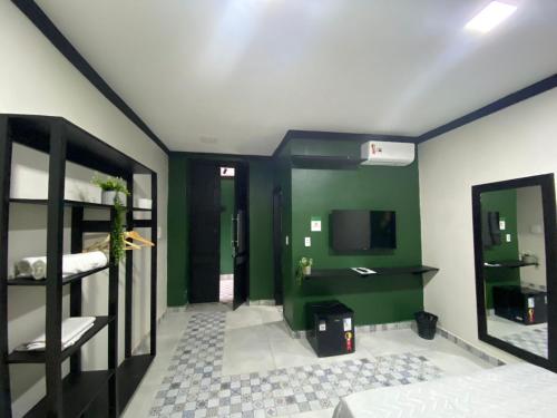 Habitación con paredes verdes, TV y literas. en Pousada Point en Aracati