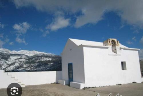 una pequeña iglesia blanca con montañas nevadas en el fondo en house FYNTIKAKH - SKALA, en Sinoikismós Kámbos