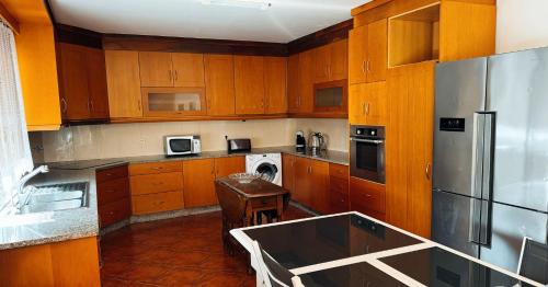 a kitchen with wooden cabinets and a stainless steel refrigerator at Villa Casa Brandao in Póvoa de Varzim