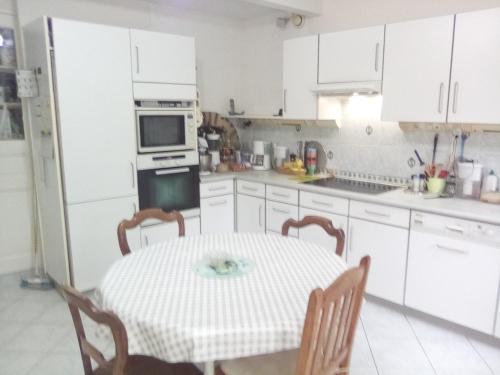 a white kitchen with a table and a microwave at Maison de village in Pévy