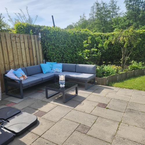 a blue couch and a table on a patio at Vakantiehuis op Villapark Oesterbaai aan zee , met speeltuin grenzend aan de tuin in Wemeldinge