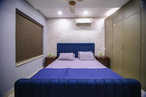 Cama grande azul en habitación con ventana en Hotel and apartments inn en Lahore