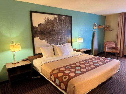 a hotel room with a bed and a painting on the wall at Super 8 by Wyndham Mount Vernon, IL in Mount Vernon